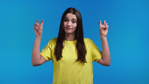 Spanish woman showing with hands and two fingers air quotes gesture, bend fingers isolated on blue background. Not funny, irony and sarcasm concept.