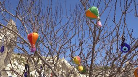 Cute small traditional turkish handcrafted decorative bright hot air balloons souvenirs hanging outdoors on branches of tree. Cappadocia, Turkey