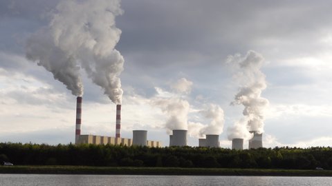 A stable view of a coal-fired power plant with smoking chimneys. The shot was taken in soft, natural light.Bełchatów