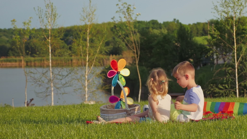 A little boy and girl on family picnic hug each other while sitting on the grass in the park. True friendship, friends for ages.