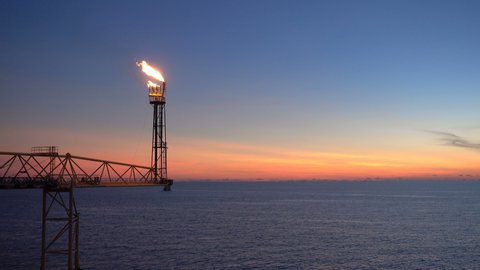 flare burning bridge of oil and gas platform or offshore platform with sun rise and beautiful clouds in the sea for oil and gas industry concept.	