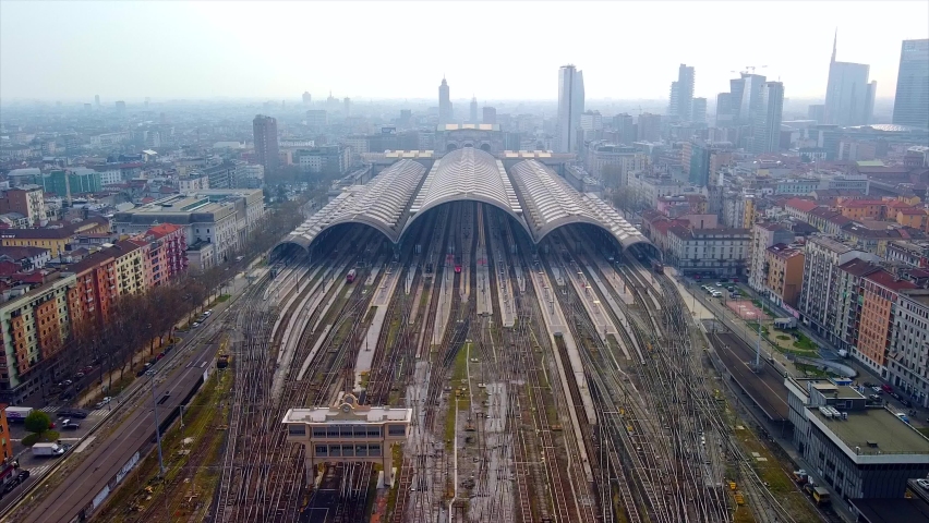 Aerial view of the station. Trains arrive at the station. An old wide arched structure of metal and glass above the station pillars. Tourism. Skyline with tall buildings. Italy, Milan, June 2021  Royalty-Free Stock Footage #1074718580
