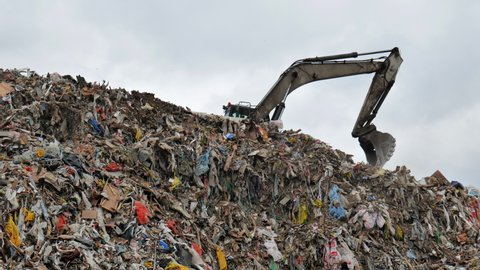 An excavator working at a landfill near the city.