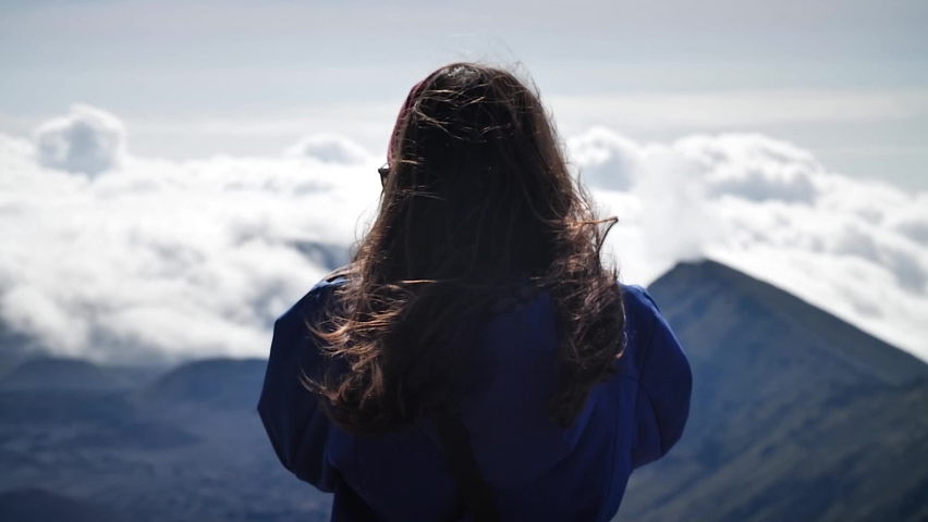 Young woman photographing clouds above the mountains in Haleakalā National Park, Maui, Hawaii. Mid angle, parallax movement, slow motion, HD.