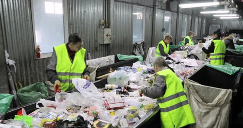 NOVOSIBIRSK, RUSSIA - JUNE 1, 2021: Garbage containers in the room. Heaps of plastic, cellophane. People are sorting the trash by hand. Recycling. Environmental protection concept.
