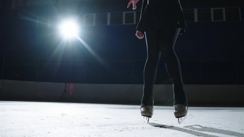 Slow motion: Cinematic shot of young female artistic figure skater is performing a woman's single skating choreography on ice rink before start of a competition. Concept of freedom