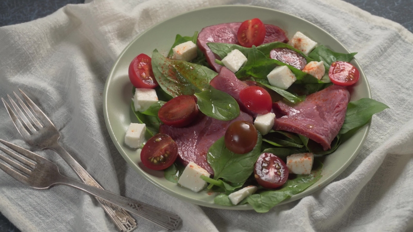 Salad with beef, tomatoes, fresh spinach and feta cheese over tablecloth rotation