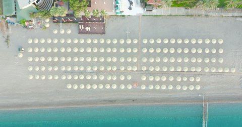 Concept of summer vacation. View from above, stunning aerial view of an amazing beach with beach umbrellas and turquoise clear water. Top view on a sun lounger under an umbrella on the sandy beach.