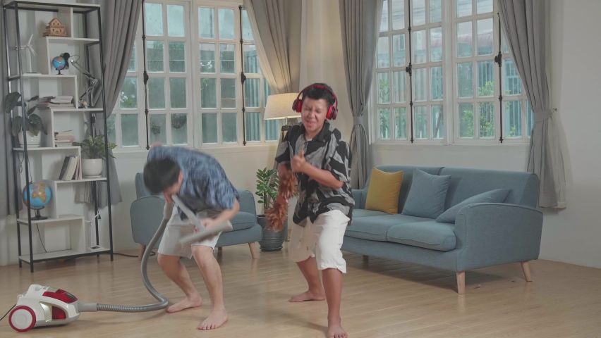 Cheerful Young Asian Father And Son Cleaning Up They Home And Singing
