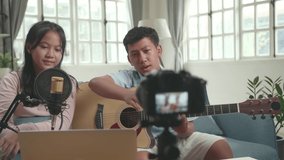 Asian Boy With Guitar And Girl Read Comment On Laptop While Live Streaming. The Children Is Broadcasting Live On The Internet
