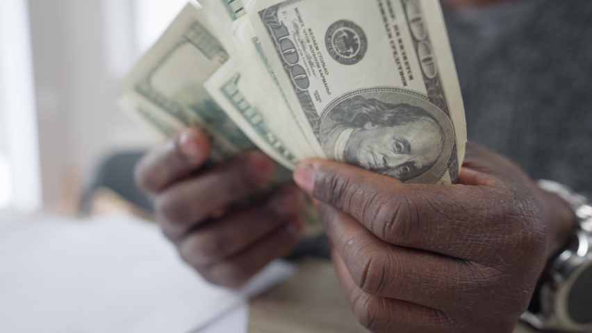 Close-up male African American hands counting money. Unrecognizable young man calculating cash dollars indoors at home. Finance and richness concept | Shutterstock HD Video #1074743003