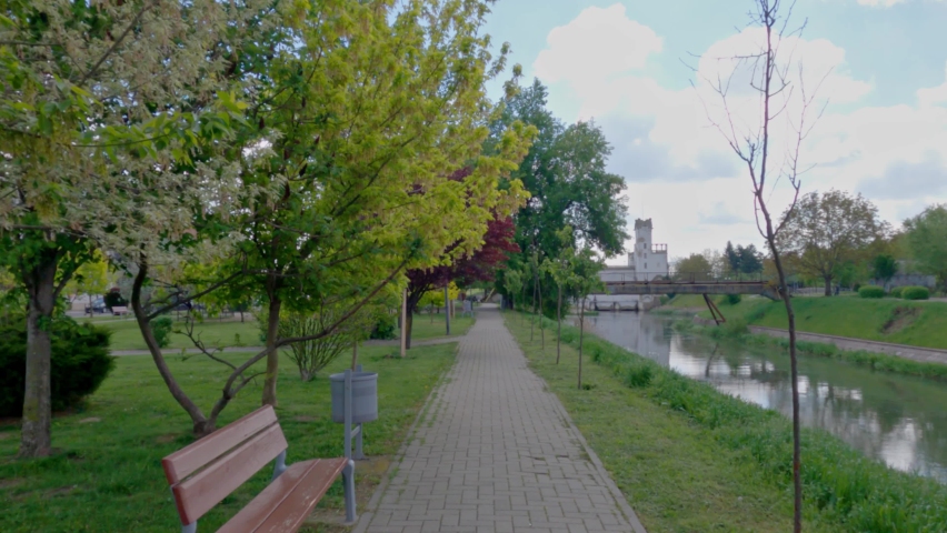 The pavement in the Parcul Uzinei park surrounded by greenery and a river in Timisoara, Romania