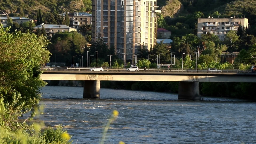 A view of cars driving on a bridge over a river on a sunny day