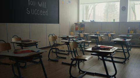 Modern classroom with desks and chairs in school. Interior view of empty elementary school class. School supplies lying on wooden tables in empty school auditorium. Study concept 