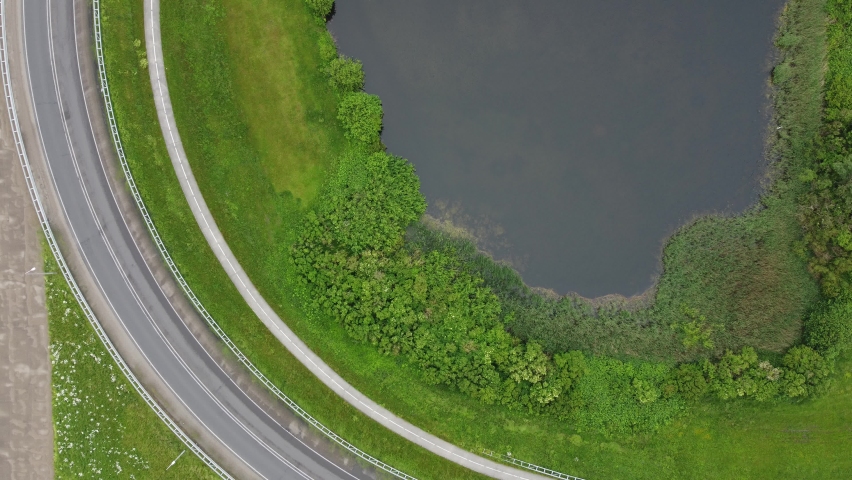 Cars driving over a provincial road near a body of water 