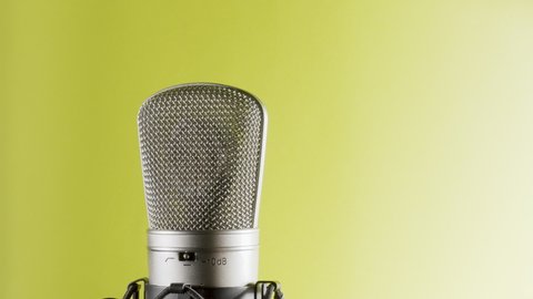 Studio microphone on an anti vibration stand, rotating. Professional audio recording equipment on yellow to white background.