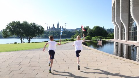 Boys run towards the Canadian parliament with Quebec and Canadian flags