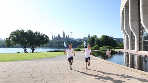Boys running to camera with Quebec flags in front of parliament