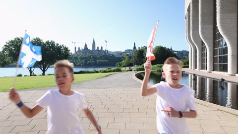 Boys running to camera with Quebec and Canadian flags in front of parliament