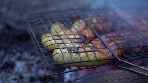 Sausages are grilled on the barbecue grill in the open air. Grilled food, grilled and smoked on charcoal grills. a bonfire is burning. delicious sausages on the grill rack. Picnic food.