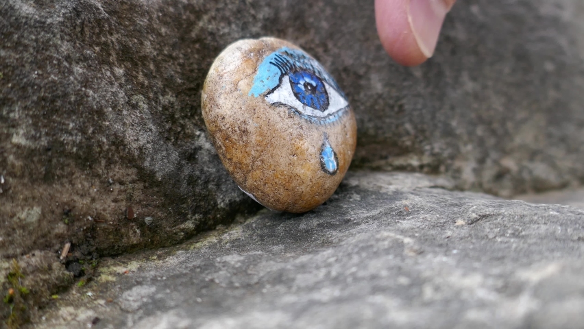 Kindness rock with blue eye and teardrop painted on