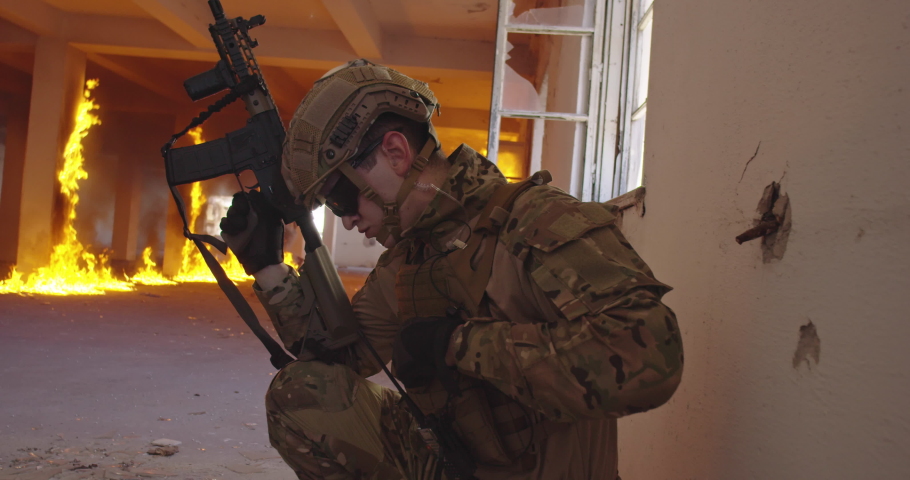 Modern warfare soldier in action near window changing magazine and take cover. Shooting trough a window in urban battlefield.