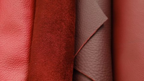 Rolls of burgundy and red leather. Rotation.genuine leather surface.Red genuine leather assortment . Raw materials for making accessories, shoes and clothes made of genuine leather