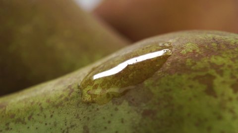 Droplets fall on the peel of a fresh ripe pear in slow motion. Macro shot. Cleaning fruit concept