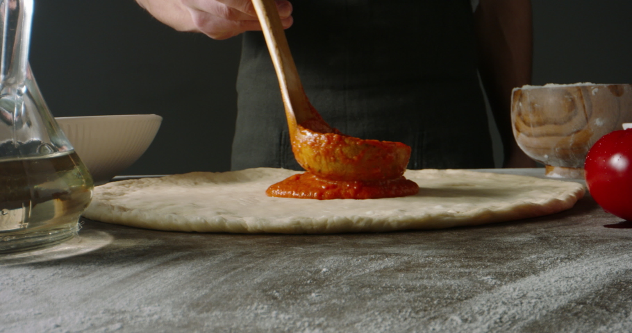 Professional chef is cooking pizza, applying delicious tomato sauce on dough with a ladle. Pizza cooker spreading the sauce. Food and drink close up 4k footage Royalty-Free Stock Footage #1074765962