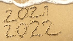 Message Year 2021 replaced by 2022 written on beach sand background. 
Good bye 2021 hello to 2022 Lapping waves happy New Year coming concept. - Powered by Shutterstock - Get 15% off with code: PIKWIZARD15