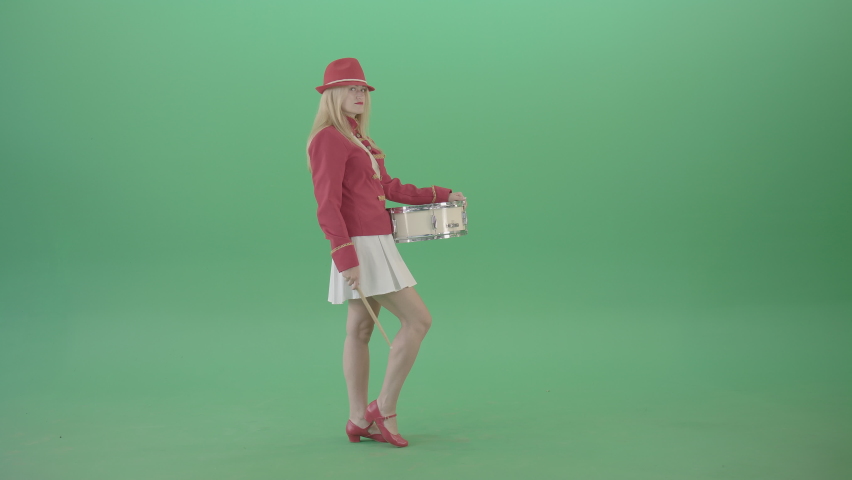 Side view marching girl play white snare drum in red uniform. Attractive young woman in military red and white costume marching playing drums percussion on green screen. 