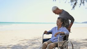 Asian senior couple tourist smile and pose by hands symbol to camera video call and make selfie by smartphone at beach. Couple elderly retire rest and relax wife is disabled and sitting on wheelchair. - Powered by Shutterstock - Get 15% off with code: PIKWIZARD15