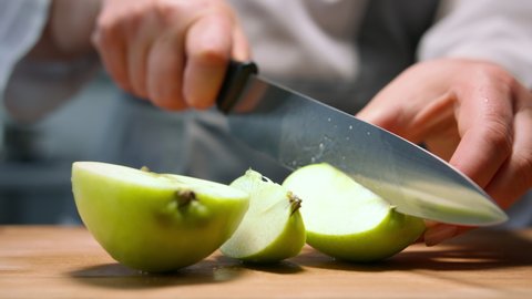 Female hands cut green apple in pieces. Close up