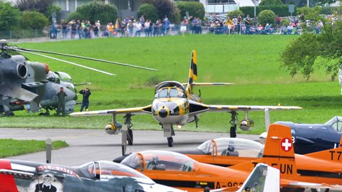 Mollis Switzerland AUGUST, 16, 2019 Historic Cold War military fighter jet taxi to the airport parking lot among many other planes. Hawker Hunter vintage plane of Swiss Air Force in 4K