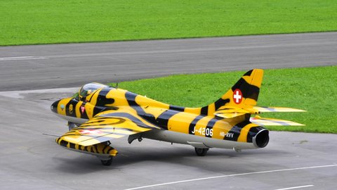 Mollis Switzerland AUGUST, 16, 2019 Cold War single-engine jet military aircraft with beautiful yellow and black livery taxies on the runway seen from behind. Hawker Tiger Hunter of Swiss Air Force