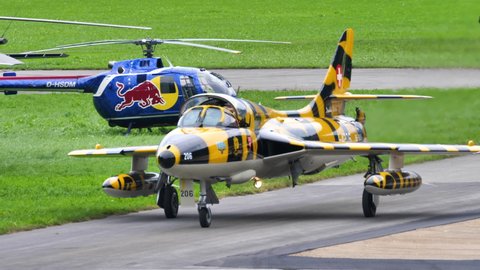 Mollis Switzerland AUGUST, 16, 2019 Close-up of a vintage aircraft of the cold war era in yellow and black tiger livery taxiing on airport runway. Hawker Hunter fighter jet of Swiss Air Force in 4K