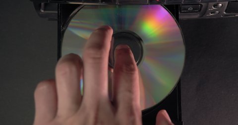 A hand inserts a CD into the player. Music or data recorded on a laser compact disc.