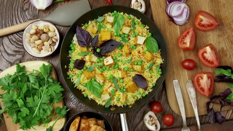 Vegetable rice with green peas, carrots, tofu and mushrooms on wooden background. revolves and approaches