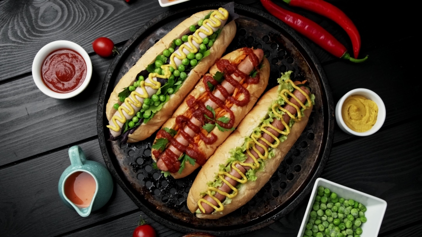 Vegeterian hot dogs served with tomatoes, avacado, onion and buns over wooden background. Top view, flat lay Royalty-Free Stock Footage #1074791741