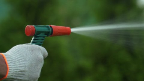 Gardening and maintainance- close up of man hands with hose watering the lawn