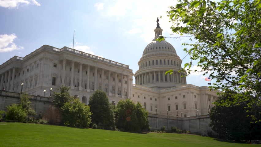 Pushing in to the shadow side of the US Capitol with trees overhead.