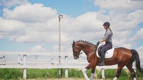 A female jockey riding on a dark bay horse. Competitive woman riding on her horse. The horse wearing stockings. Mane is done in a braid. Beautiful cloudy sky against the wooden fence in the background - Powered by Shutterstock - Get 15% off with code: PIKWIZARD15