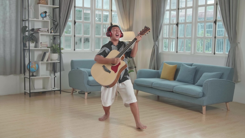 Asian Boy Playing Guitar, Sing A Song And Dancing At Living Room
