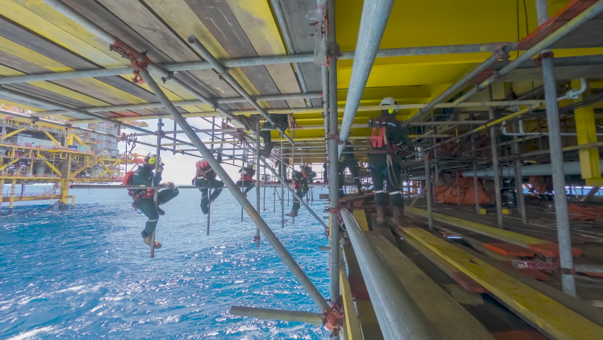 4K time lapse of scaffold erector team with falling protection hanging on scaffold frames below oil and gas platform during working overboard in the middle of the sea. | Shutterstock HD Video #1074797900