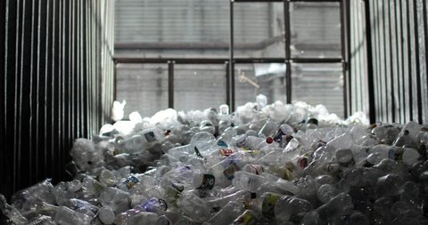 NOVOSIBIRSK, RUSSIA - JUNE 1, 2021: A lot of plastic bottles with caps and labels are in the storage with a window in the background. Storage, reuse and processing. Environmental protection concept.
