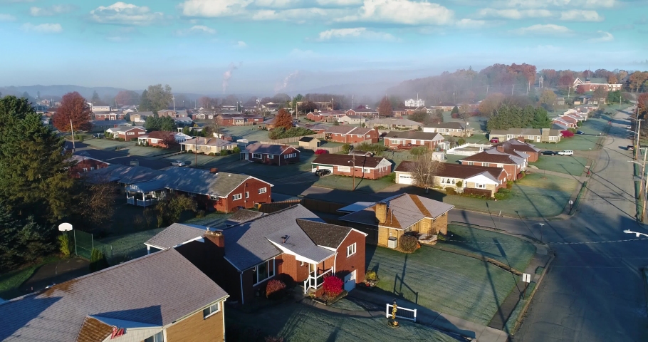 A forward rising aerial establishing shot of a typical Western Pennsylvania residential neighborhood on a frosty late-Autumn morning. Tilt up to sky. Pittsburgh suburbs.  	