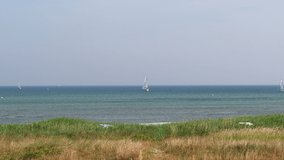 4K 60fps video of beautiful view of dunes on beach and blue sea with white sailboat at sunny summer day on Baltic sea in Germany