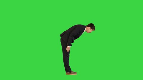 Asian man in office suit making a bow on a Green Screen, Chroma Key.