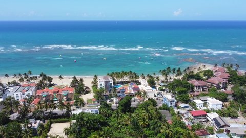 Aerial view of the public Kite beach in Cabarete. White sand, tall palm trees and turquoise water. Many surfers ride the waves on a strong wind. Best Kiteboarding Spots Worldwide