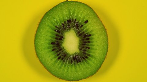 kiwi slice rotating top view on yellow background.Macro food.Looped rotation.Healthy eating concept.Organic food.healthy food,bio food.Green fruit.